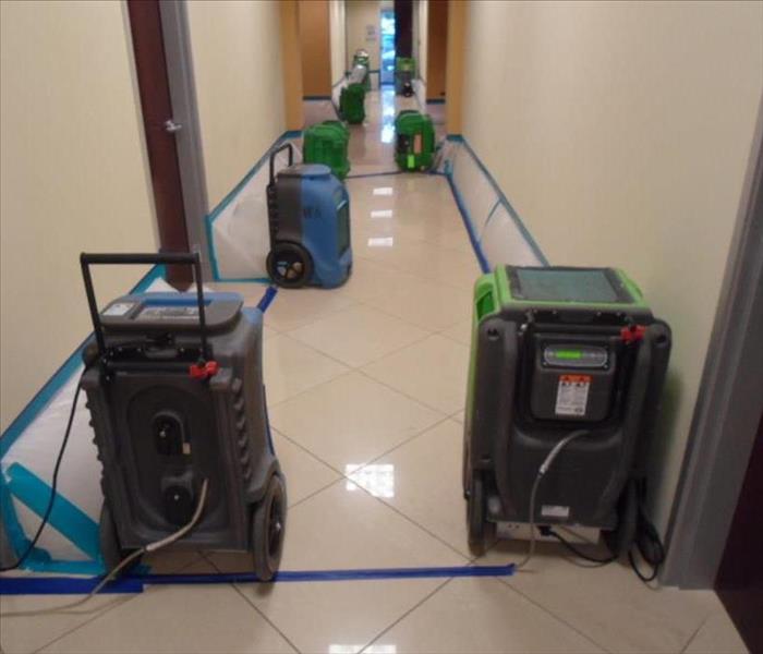 Office facility with water damaged the hallways. Dehumidifiers and air movers are removing moisture from the affected area.